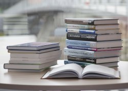 Two stacks of books on a table, with one book open in front of them