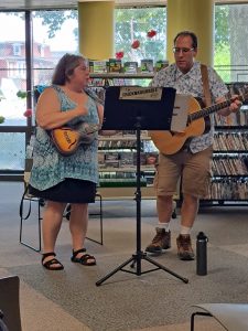 Duo playing guitars and singing at the library